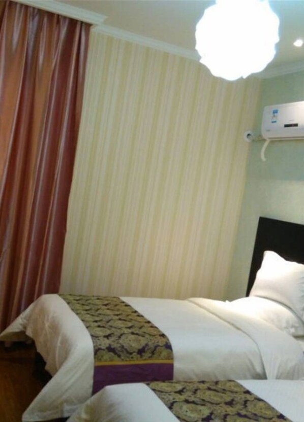 Una habitación de hotel con cama, cortinas y un equipo de aire acondicionado.