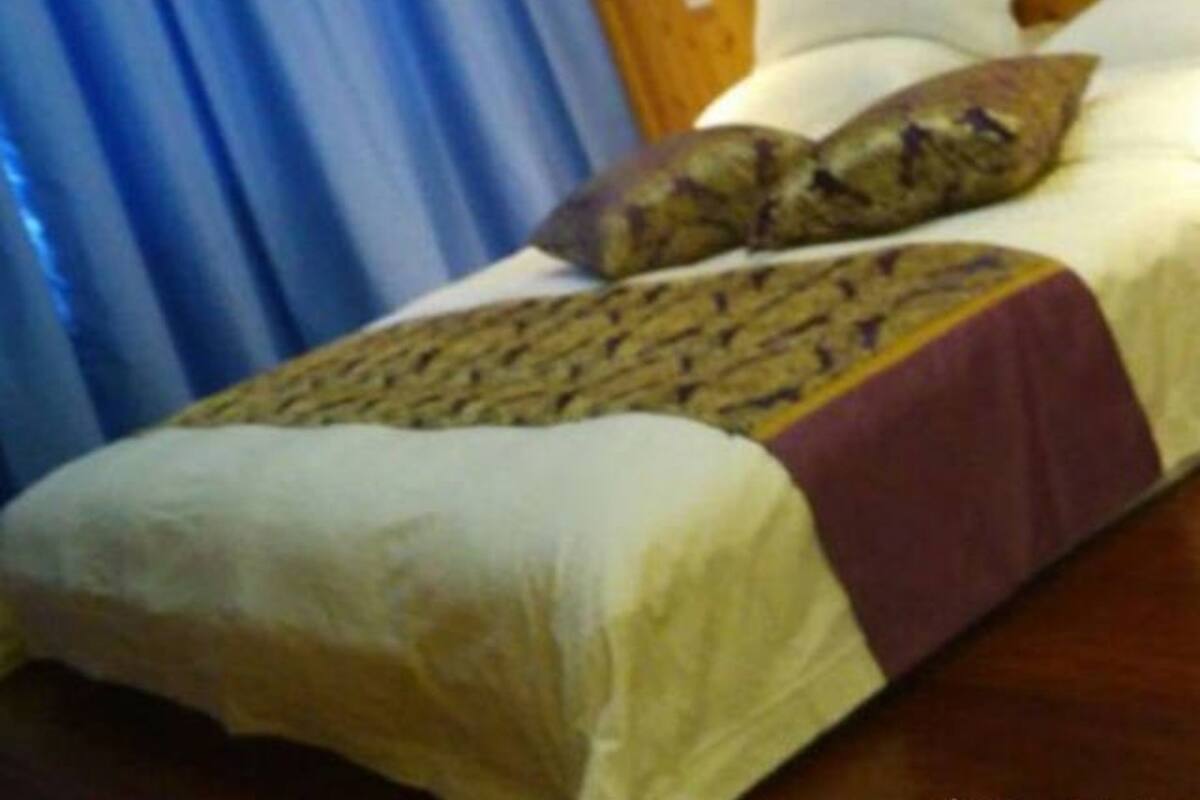 A bedroom with a wooden headboard, a bed with white bedding, and a blue curtain.