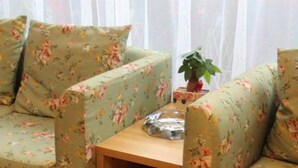A room with two floral-patterned sofas, a small wooden table, and a potted plant. - 118 Inn Hangzhou Xiaoshan Nanxiu Road (Hangzhou)