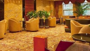 A hotel lobby with a patterned carpet, seating area with chairs and tables, decorative lighting, and large windows. - Tieliu Business Hotel (Hangzhou)