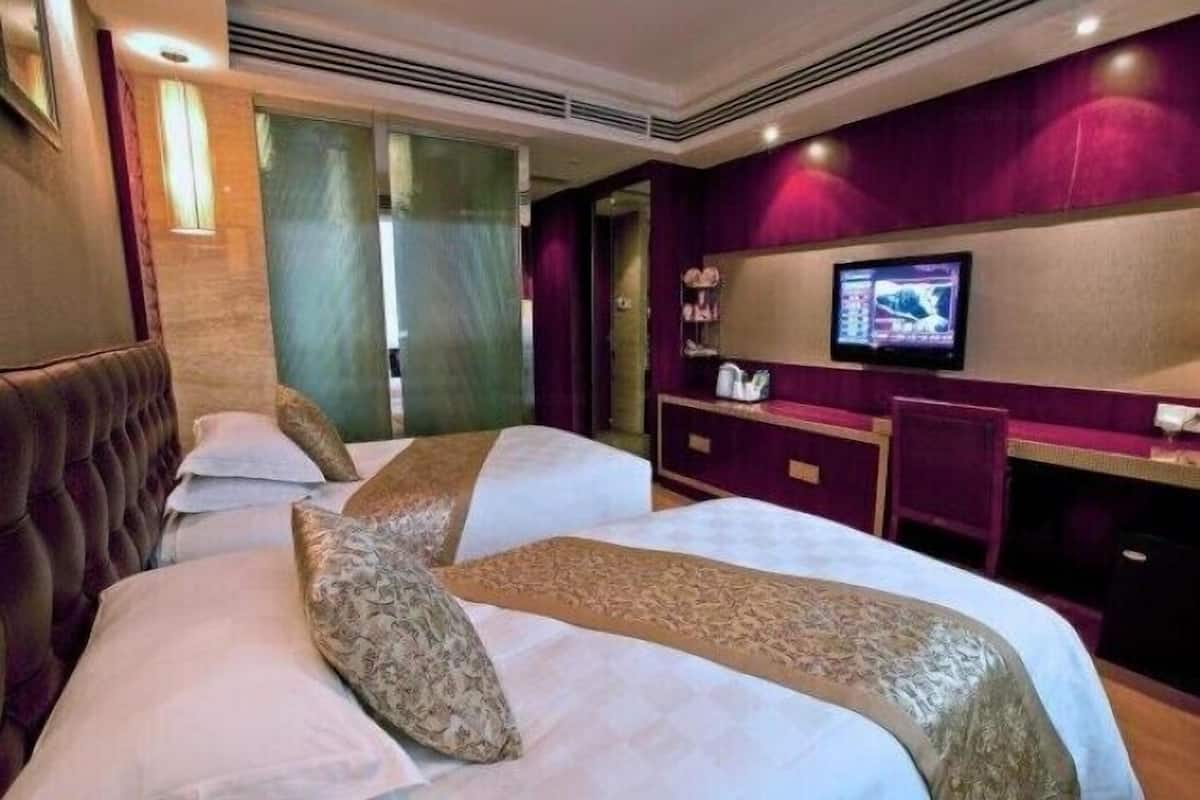 Quarto de hotel com duas camas, uma televisão e uma escrivaninha.