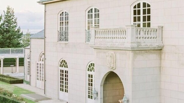 Un edificio grande y señorial con múltiples ventanales arqueados y una entrada central.