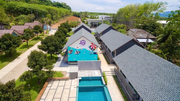 A resort with a swimming pool, multiple buildings, and a lush green landscape. - Be Leaf Resort (Thep Krasattri)