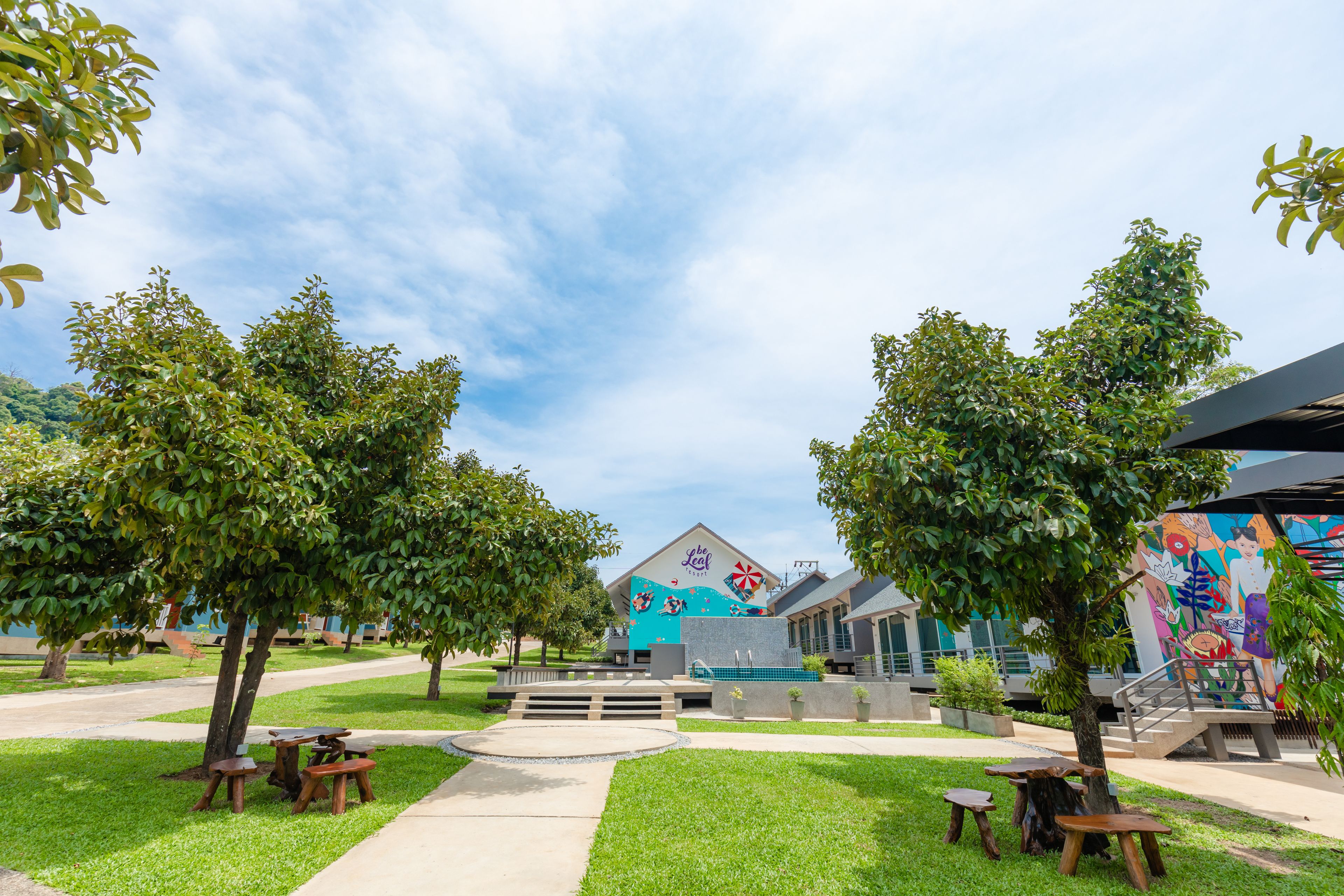 A courtyard with picnic tables, a mural, and a building with a colorful facade.