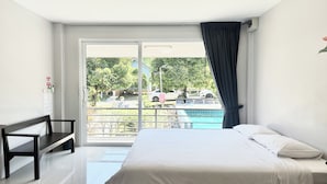A hotel room with a bed, a bench, a view of a swimming pool, and a door to the outside. - Be Leaf Resort (Thep Krasattri)