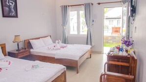 Habitación de hotel con dos camas, un escritorio de madera, una silla, una ventana con cortinas y vistas al exterior.