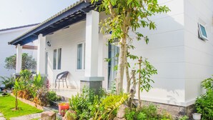 Una casa blanca con un porche cubierto, plantas en macetas y una silla.