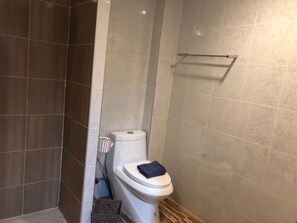 A bathroom with a toilet, a towel rack, and a shower area. - CU at Jomtien (Pattaya)