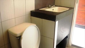A bathroom with a toilet, sink, and tiled walls. - Heilee's Guest House (General Santos)