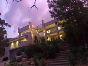 A modern multi-story building with a flat roof, large windows, and a landscaped garden with rocks and plants. - Hollywood Tree House (Burnside)