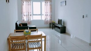 Un salon spacieux comprenant une table à manger et des chaises, un canapé, un téléviseur et un ventilateur de plafond.