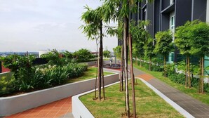 Un espace extérieur aménagé avec des allées, de la verdure et un bâtiment moderne en arrière-plan.