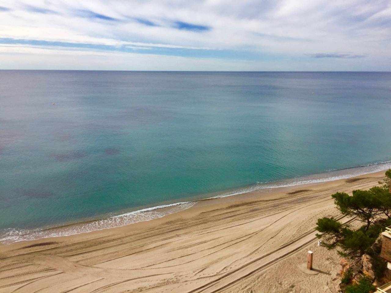 Una playa con vista despejada al océano y un camino de arena que lleva al agua.