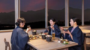 Una mesa de comedor con varios platos y bebidas, con un fondo de amplias ventanas que dan a vistas de montañas.