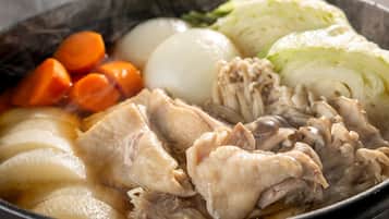 A bowl of soup with chicken, carrots, and cabbage.