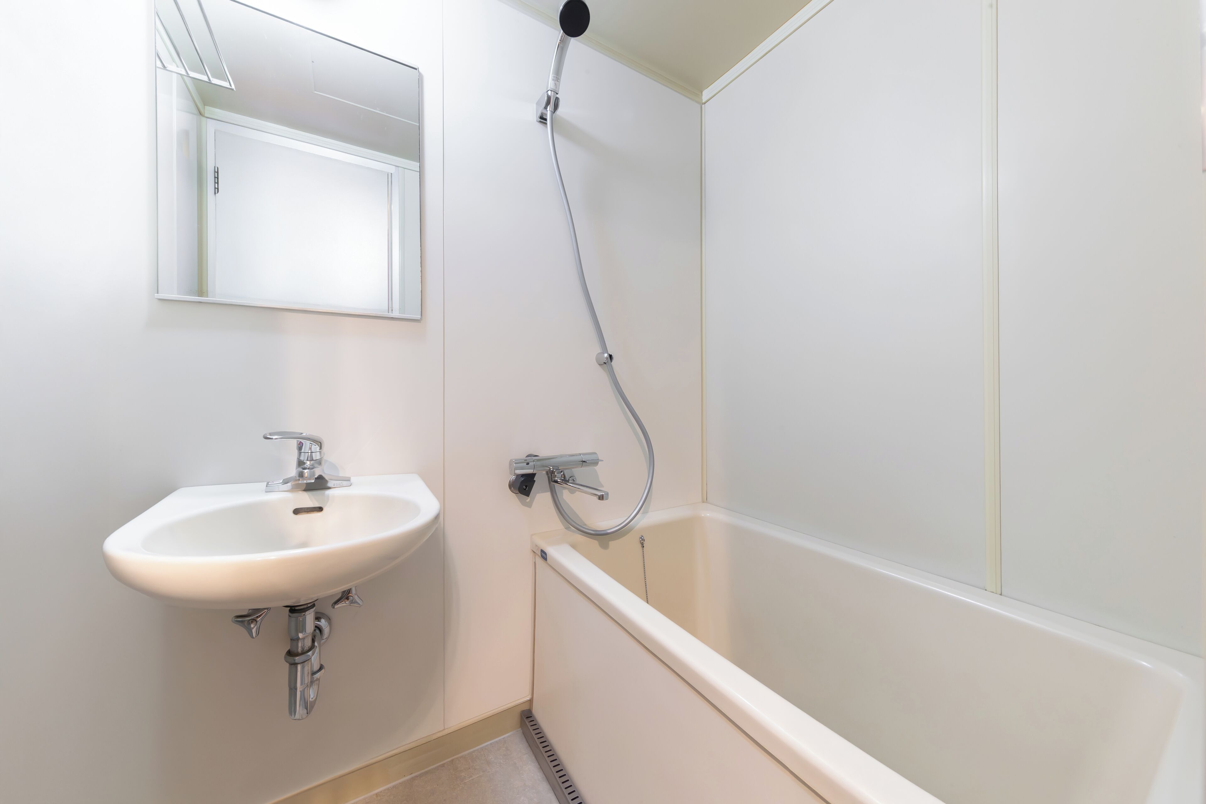 Un baño con lavamanos blanco, un espejo y ducha.