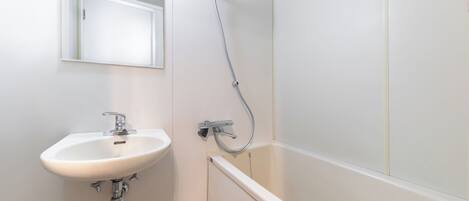 Un baño con lavamanos blanco, un espejo y ducha.