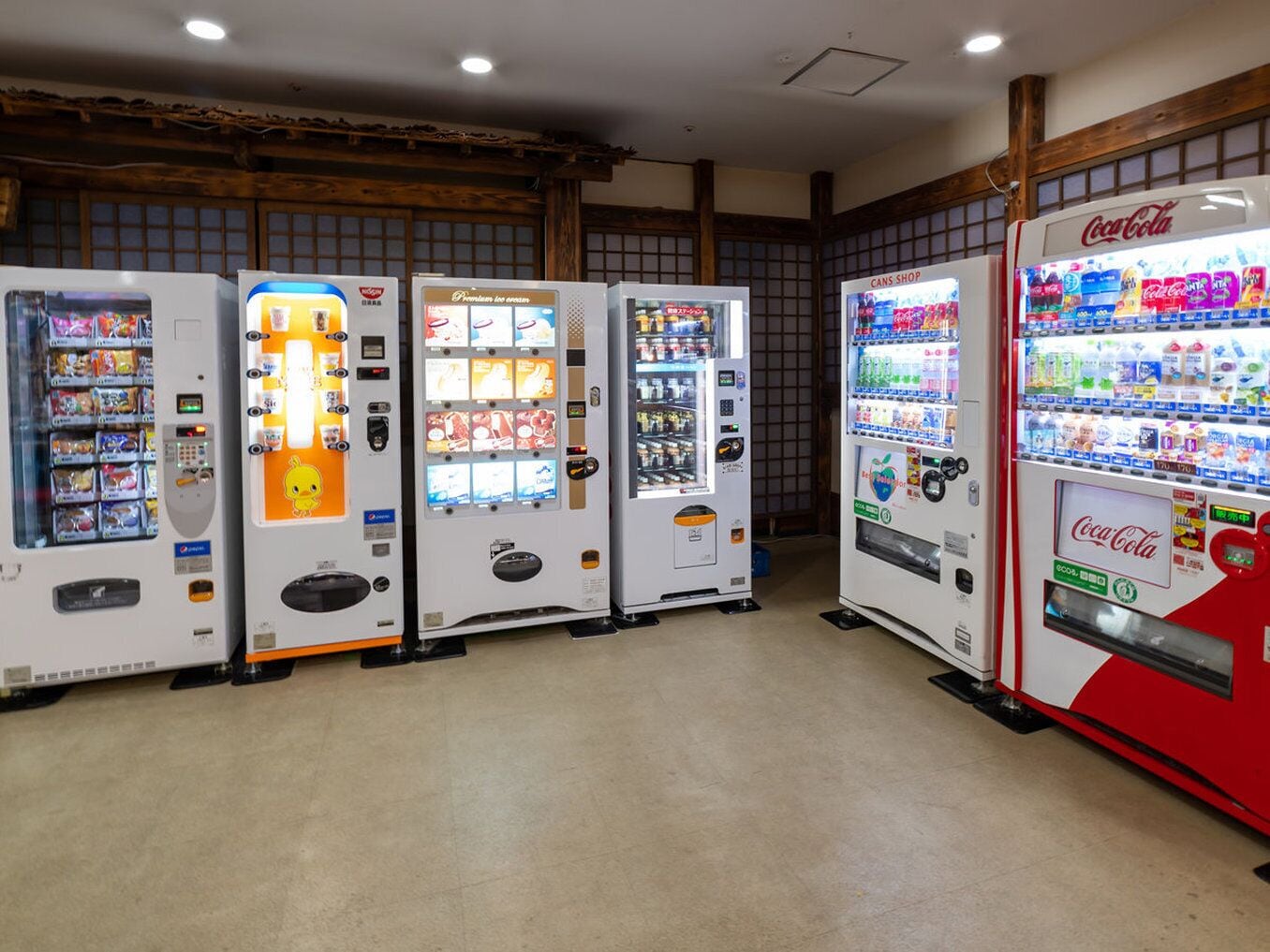 A row of vending machines in a room with wooden beams on the ceiling.