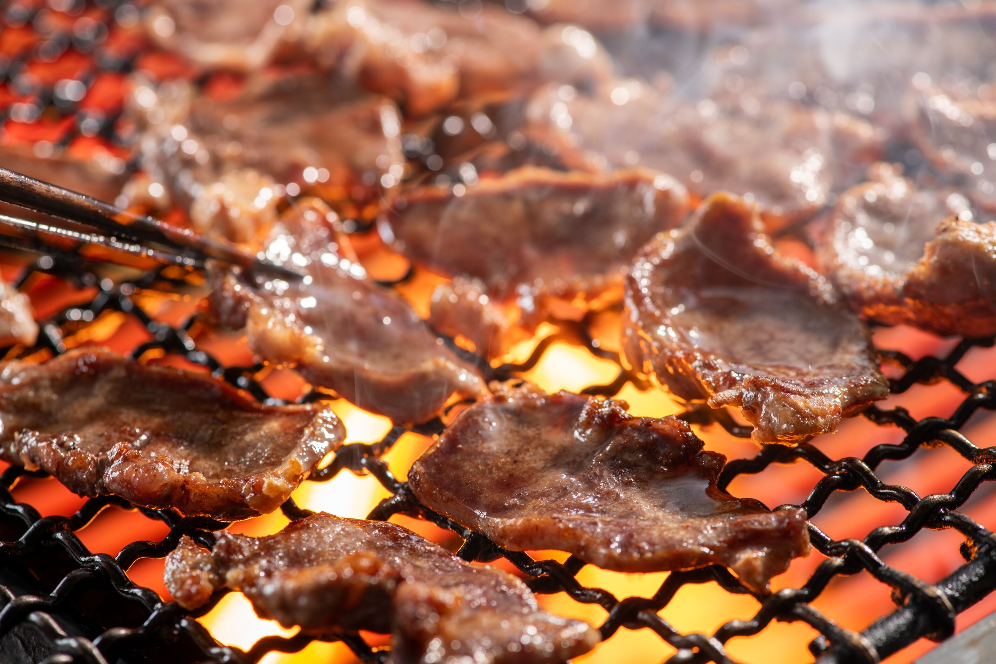 Gros plan sur de la viande en train de griller sur un barbecue.