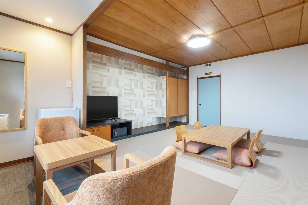 Une chambre moderne avec un plafond en bois, une télévision, un canapé et une table à manger.