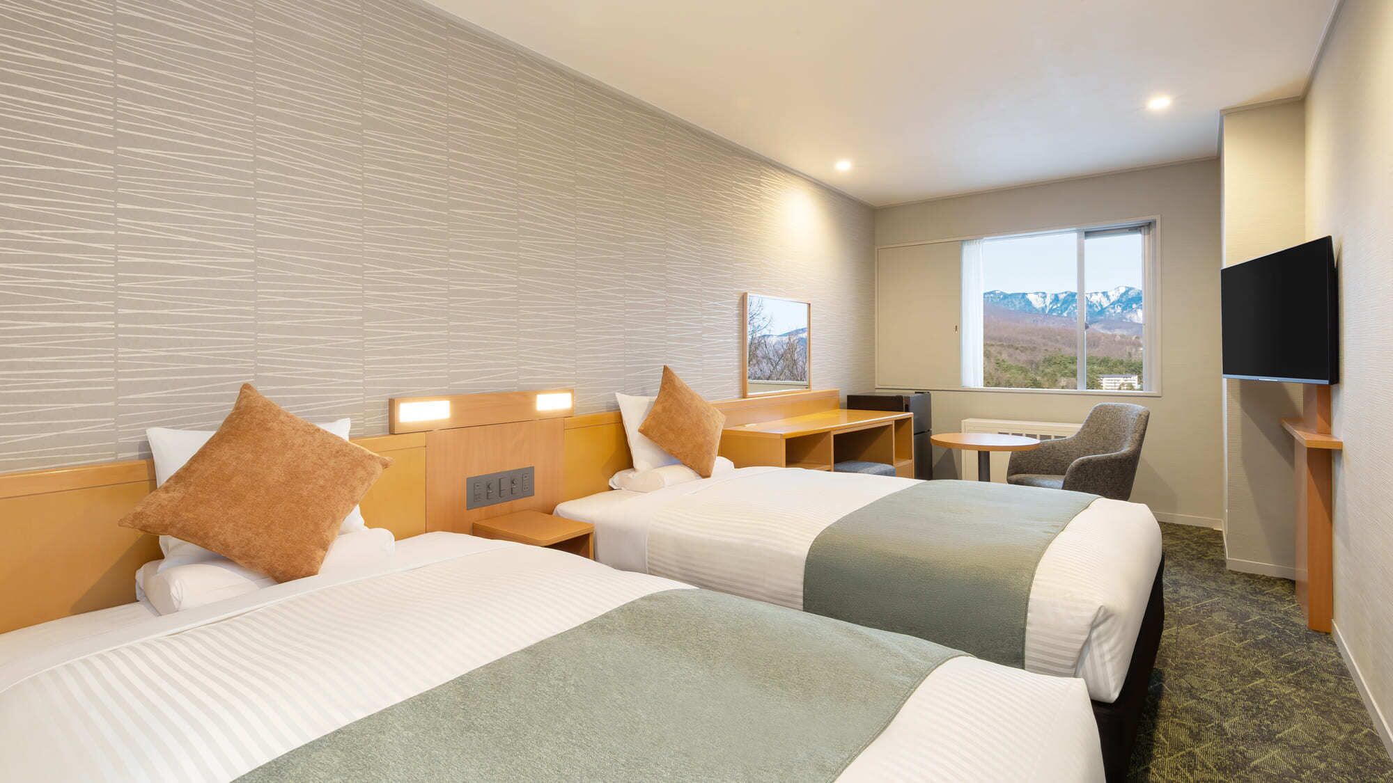A hotel room with two beds, a desk, a chair, a TV, and a window with a mountain view.