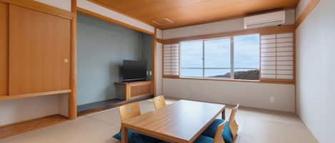 A traditional Japanese room with tatami flooring, a wooden dining table, and a television on a low stand.