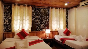 Une chambre d’hôtel avec deux lits, un plafond en bois, des murs à motifs de marbre et une table de chevet avec une lampe.