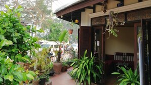Un bâtiment traditionnel doté d’une cour dallée, de plantes en pot et d’une cloche suspendue à l’entrée.