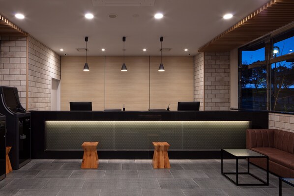A reception area with a counter, wooden stools, a sofa, and pendant lighting. - Meet Inn Narita (Narita)