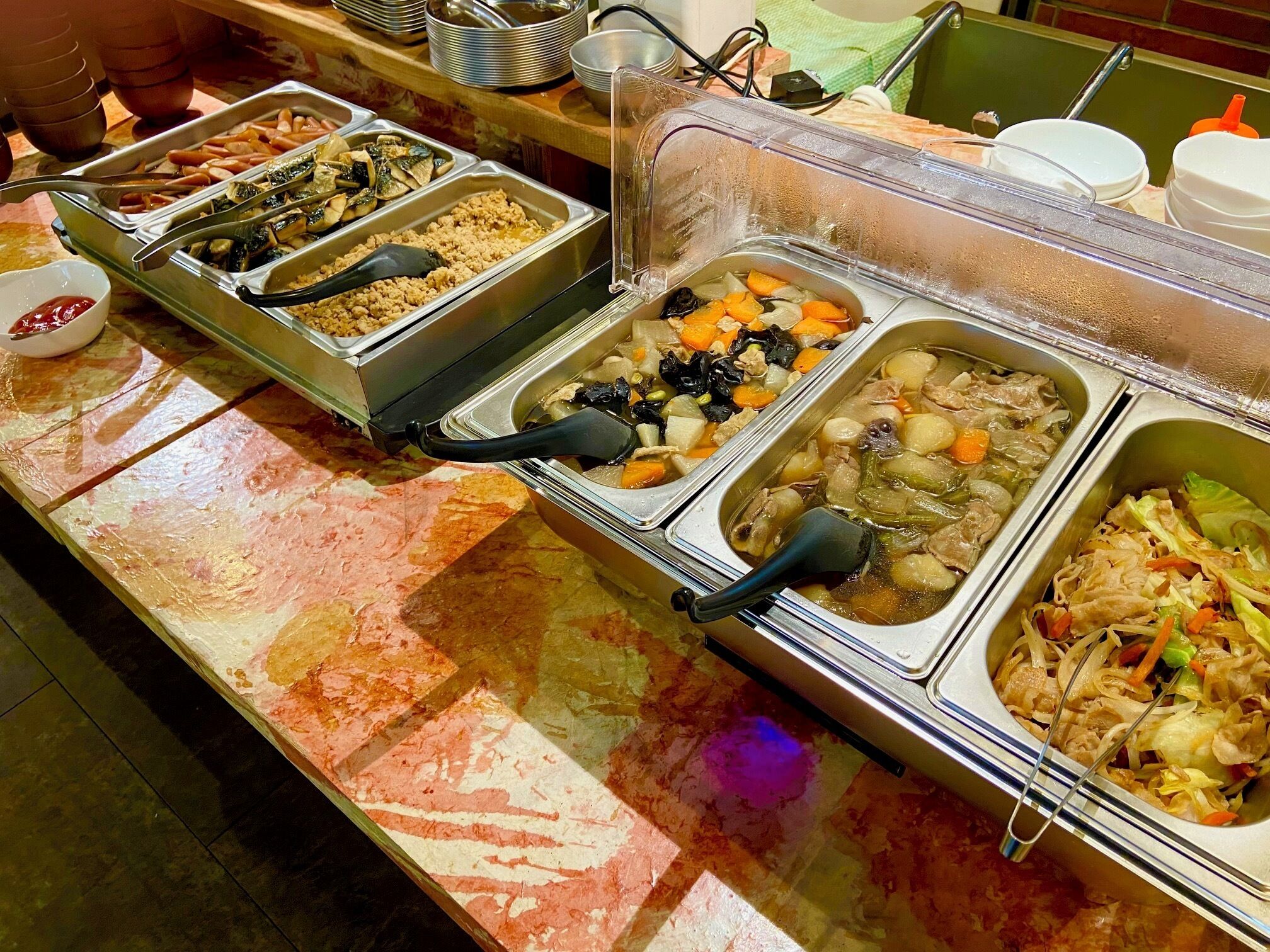 A buffet with various food options, including meats, vegetables, and grains.