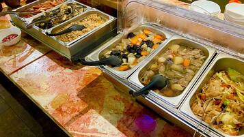 A buffet with various food options, including meats, vegetables, and grains.