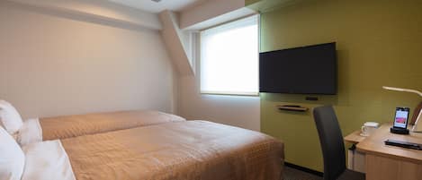 A hotel room with a bed, a desk with a chair, a television, and a window.