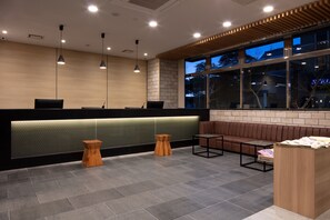A modern reception area with a reception desk, seating, and a large window. - Meet Inn Narita (Narita)