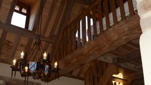 A wooden staircase with a chandelier, a stone wall, and a window with stained glass. - Gîte 3 pers. between Land and North Brittany Sea (Tréduder)