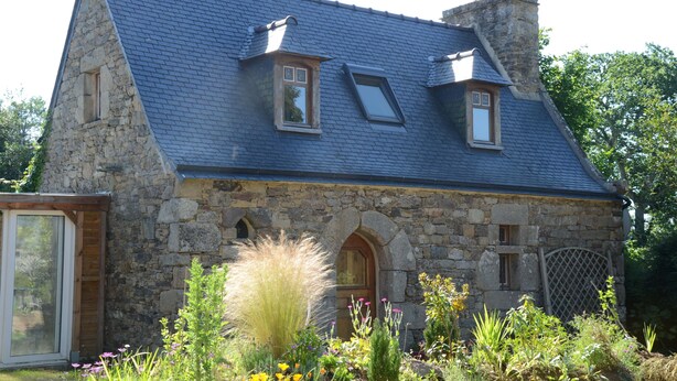 A stone house with a steeply pitched roof, a wooden door, and a small window. - Gîte 3 pers. between Land and North Brittany Sea (Tréduder)