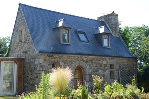 A stone house with a steeply pitched roof, a wooden door, and a small window.