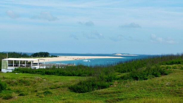 A beach with a white building, likely a hotel, in the foreground.