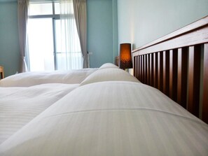 A hotel room with a large bed, a wooden headboard, and a window with curtains.