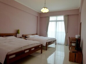 A hotel room with two beds, a desk, a chair, a television, and a large window with curtains.