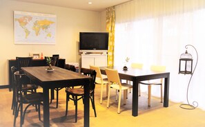 A dining area with a wooden table, chairs, a television, and a world map on the wall. - Cottage EMI (Kyoto)