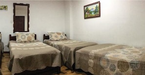 A room with two single beds, a wooden door, a framed picture on the wall, and a small table with a chair. - Hotel del Turismo (Santa Rosa de Cabal)