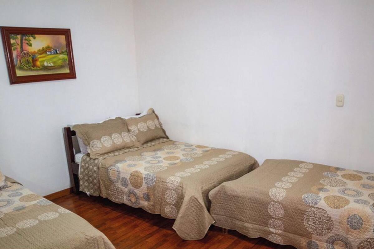 A small, simple room with two single beds and a wooden floor.