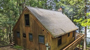 Una cabaña de madera con balcón, rodeada de árboles.