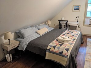 A bedroom with a bed, two bedside tables, a desk, and a chair.