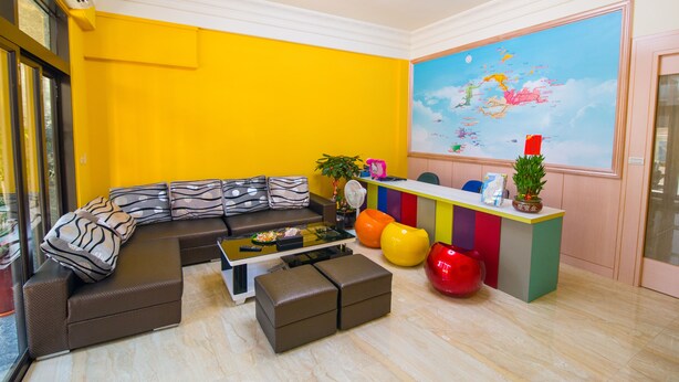 Un salon moderne avec un canapé d’angle, une table basse et des fauteuils aux couleurs vives.