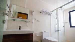 Une salle de bain moderne dotée d’une douche à parois de verre, de toilettes et d’un meuble-lavabo avec un miroir.