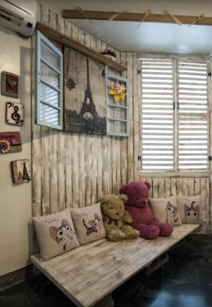 A wooden bench with plush toys, a wall with a mural of the Eiffel Tower, and a window with shutters.