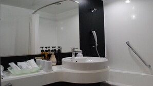 Ein modernes Badezimmer mit einem weißen Waschbecken, einem großen Spiegel und einer Dusche.