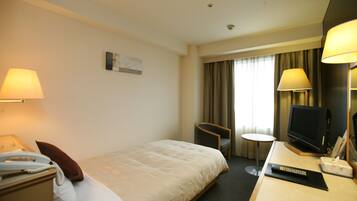 Quarto de hotel com cama, mesa de cabeceira, abajur, cadeira, televisão e uma pequena mesa.