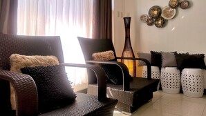 A living room with wicker furniture, a decorative wall piece, and a tall vase. - Mactan Cebu Waiting Lounge (Lapu-Lapu)